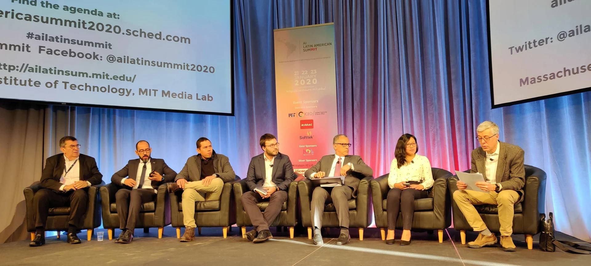 Panelists sit onstage during the AI Latin American SumMIT at the MIT Media Lab; the screen identifies the event and its January 21–23 program.