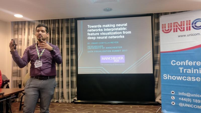 Dr. Omar Costilla Reyes presenting beside a projected slide on feature visualisation and neural-network interpretability.