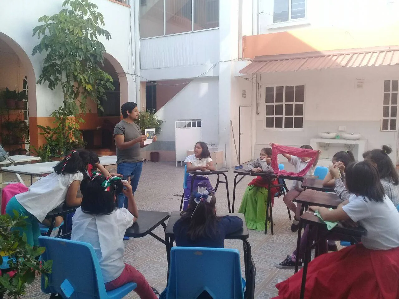 Dr. Omar Costilla Reyes holds an illustrated image while speaking to girls seated around tables at the María Inés Gasca Center.