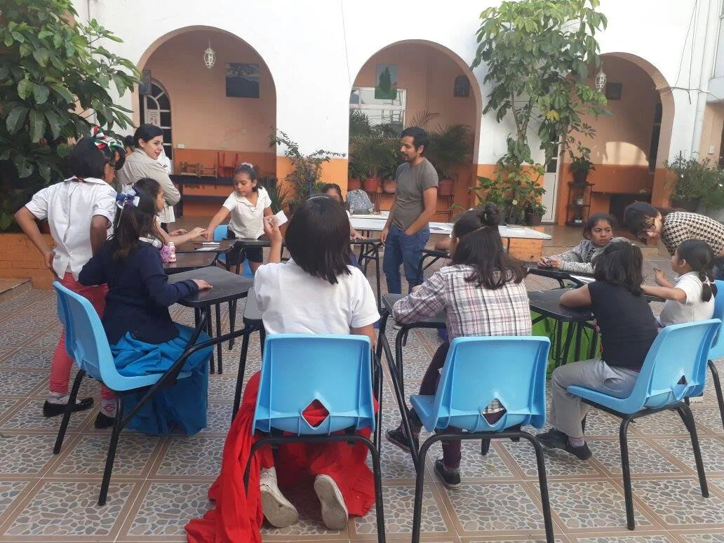 Girls gather around tables during the science talk with Dr. Omar Costilla Reyes at the María Inés Gasca Center.