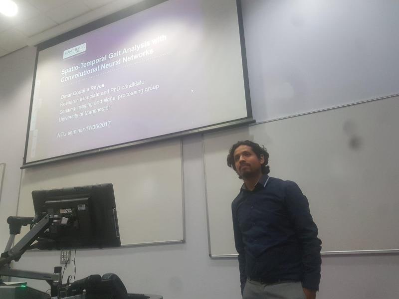 A speaker stands in a lecture room beside a projected title slide reading Spatio-Temporal Gait Analysis with Convolutional Neural Networks, marked NTU seminar 17/05/2017.