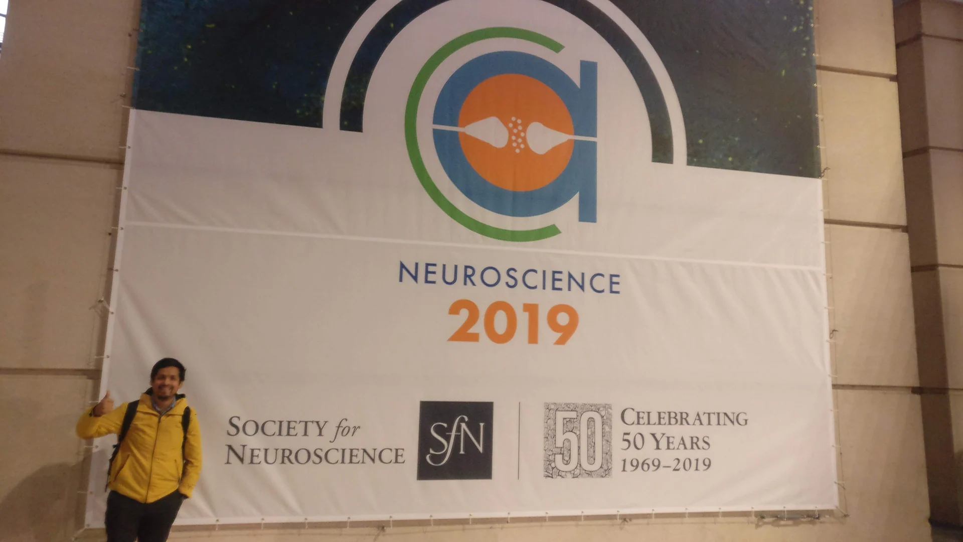 Dr. Omar Costilla Reyes beside the Society for Neuroscience 2019 anniversary banner in Chicago.