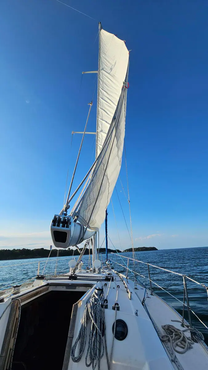 Looking forward from a sailboat beneath its white sail on Boston Harbor.