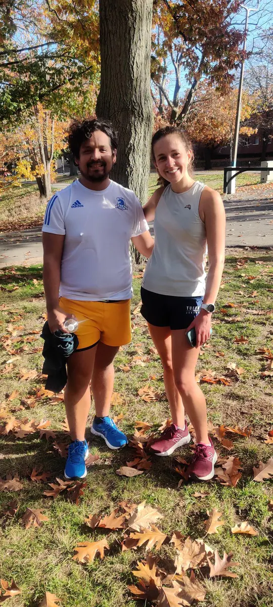 Omar and a running friend stand together in an autumn park.