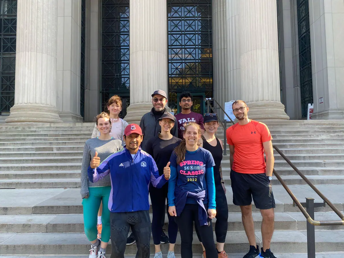 Members of the MIT Postdoctoral Association running group gather on campus steps.