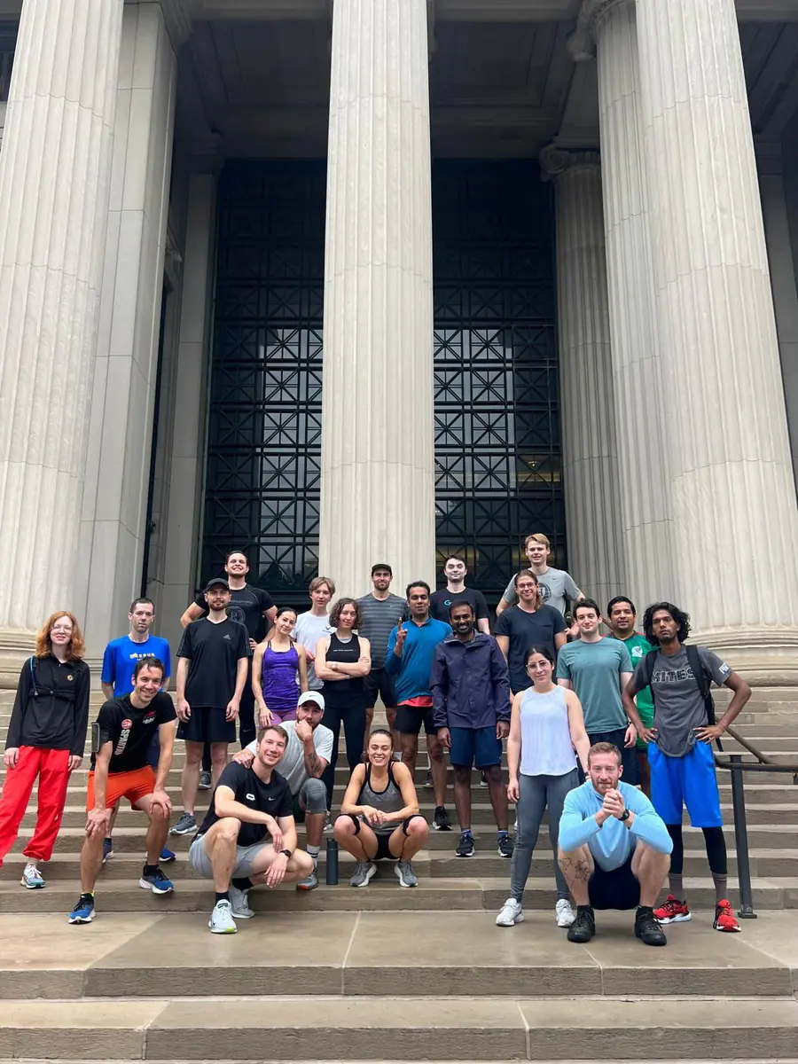 Members of the MIT Postdoctoral Association running group gather on campus steps.