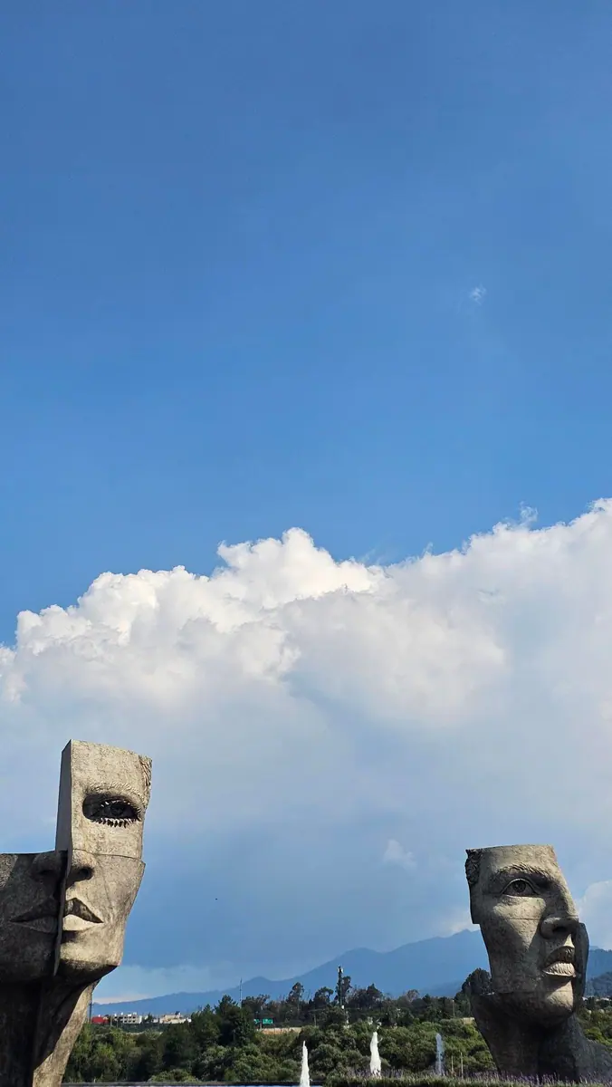 Two monumental stone faces frame the mountains in Santa Fe, Mexico City.