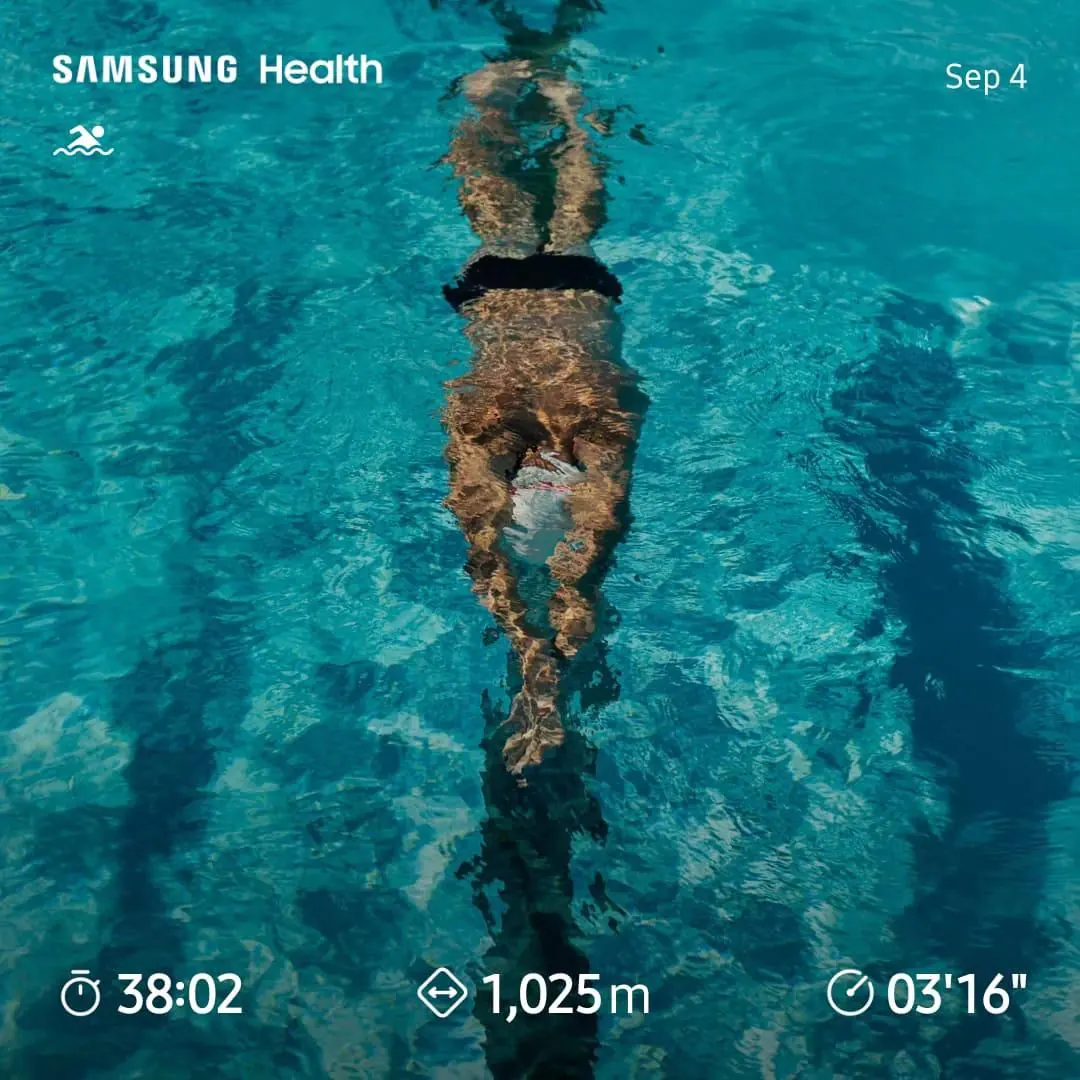 A swimmer completes a lap in a bright blue pool, with a workout summary overlaid.