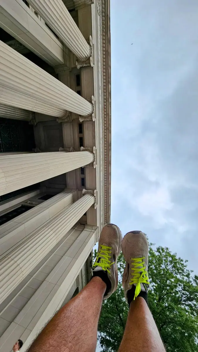 A runner’s shoes lifted toward the facade of a city building.